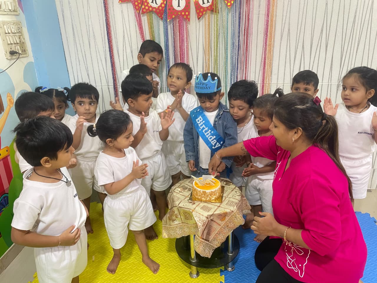 Teacher celebrating a child's birthday with classmates at Kidz Express Preschool